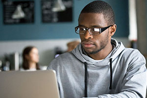 African American male with glasses using a laptop