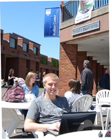 Image of student on laptop sitting outside on campus
