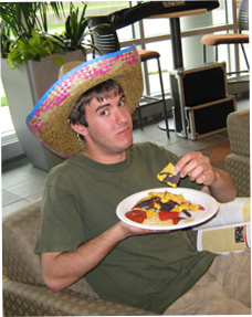 Image of male student eating with sombrero on