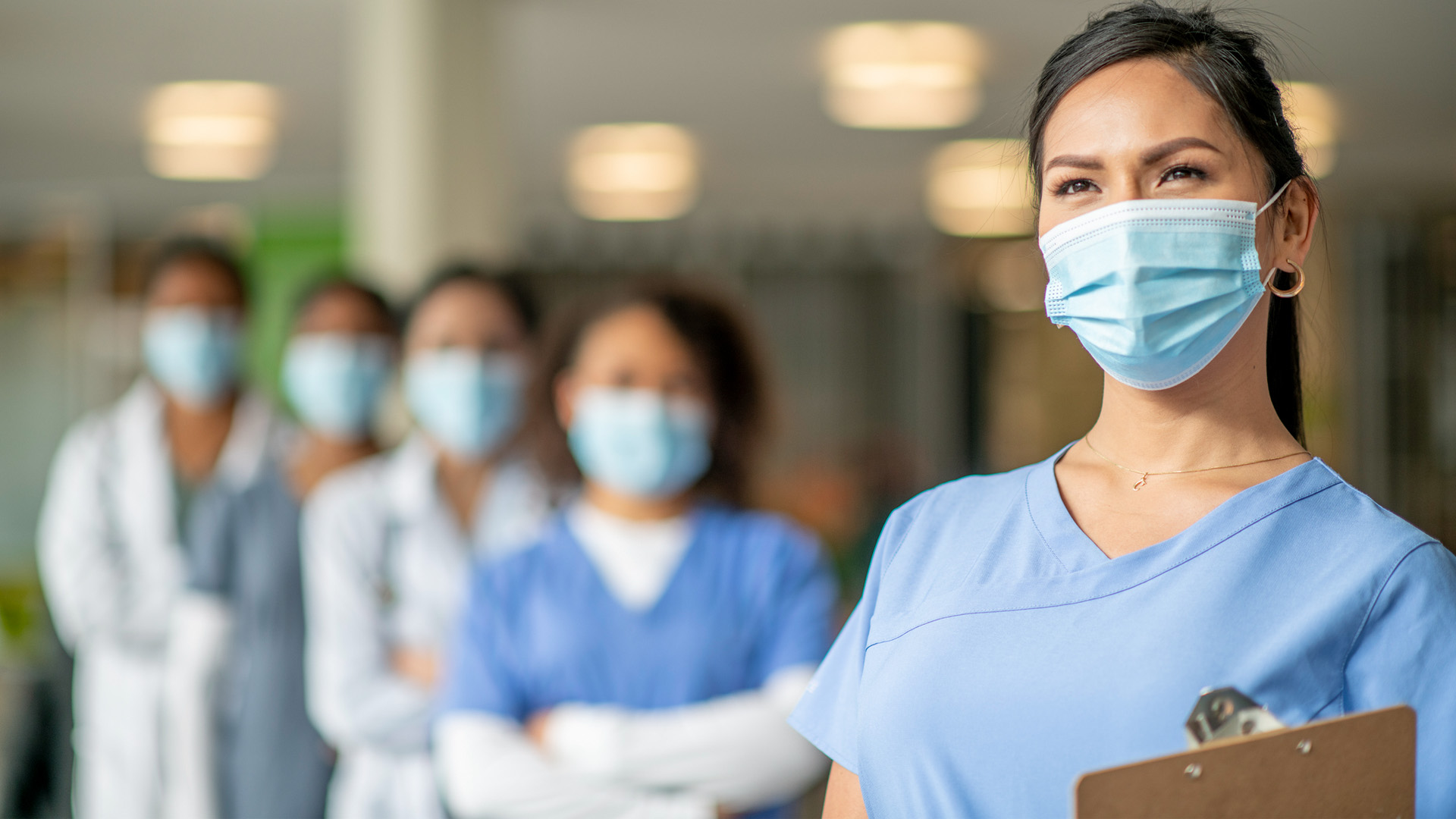 nurses standing in a line wearing masks and scrubs