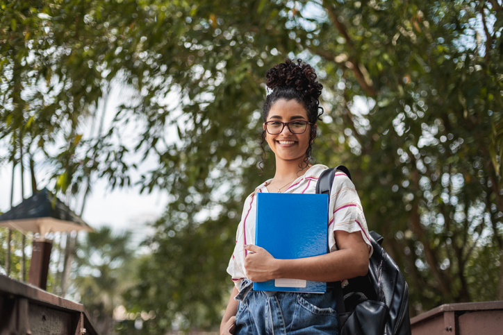 college student smiling outside with notebooks in hand