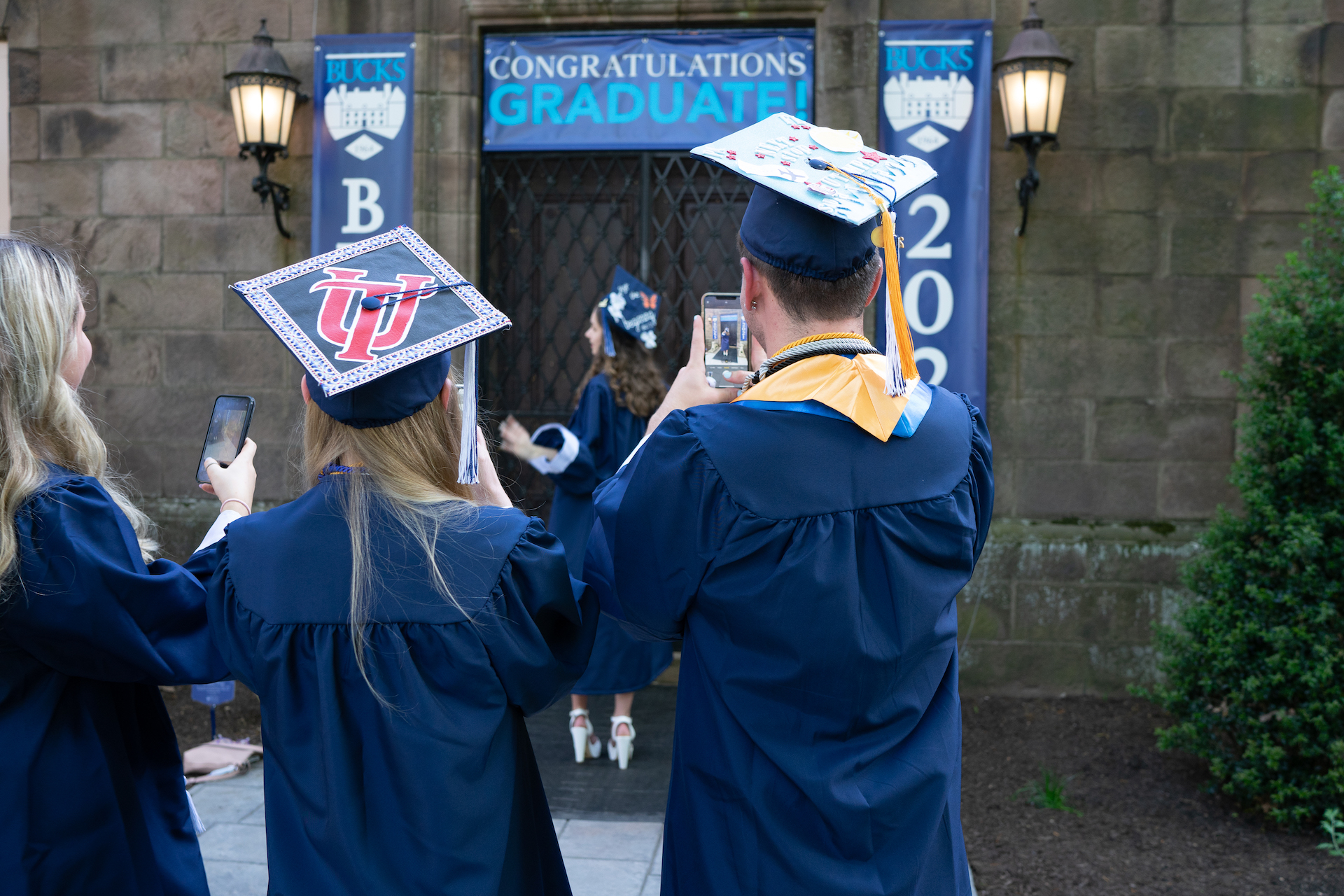 photo from behind of students in cap and gown taking photos