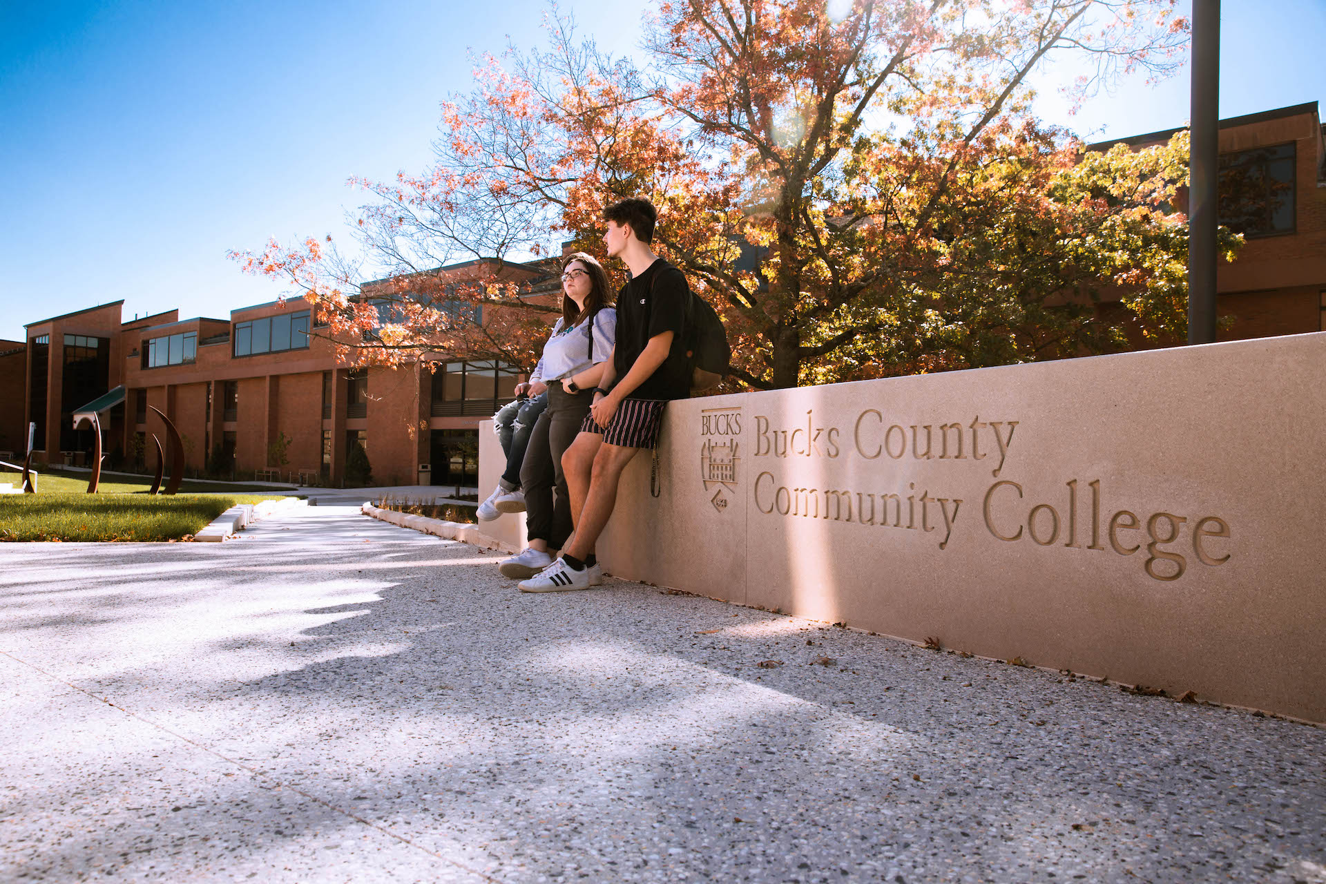 two students standing outside talking on college campus