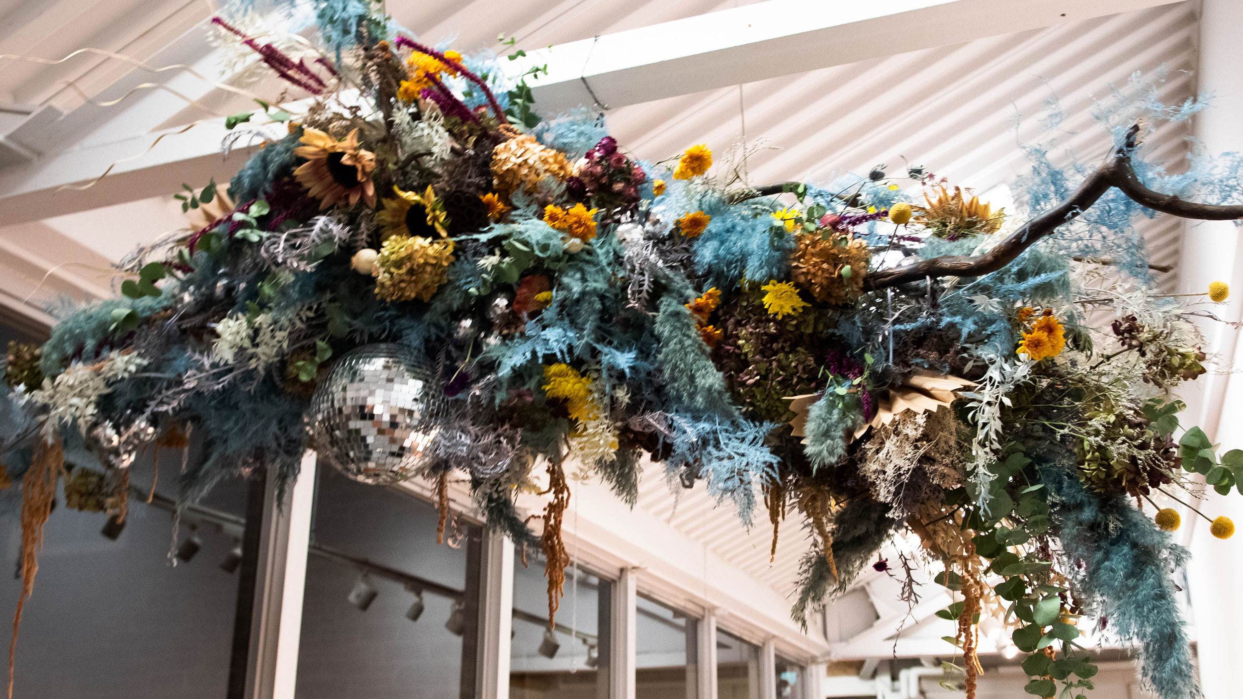 Floral installation with blues yellows and greenery from ceiling