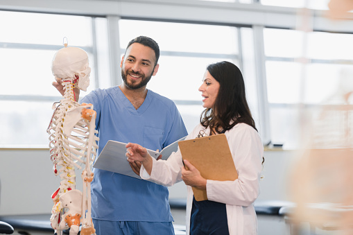 Male student in medical scrubs talking to instructor