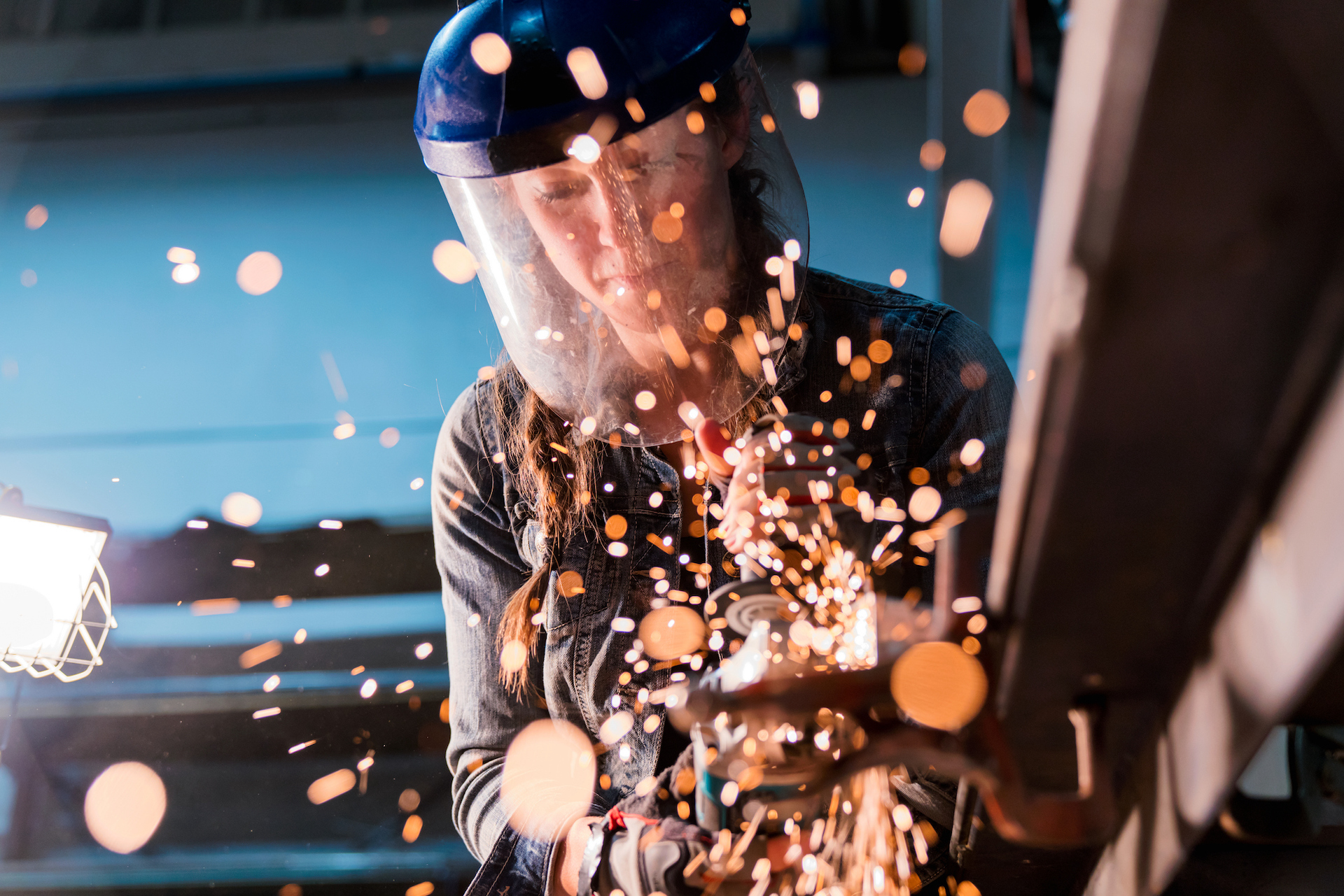 metalworker wearing protective gear with sparks flying