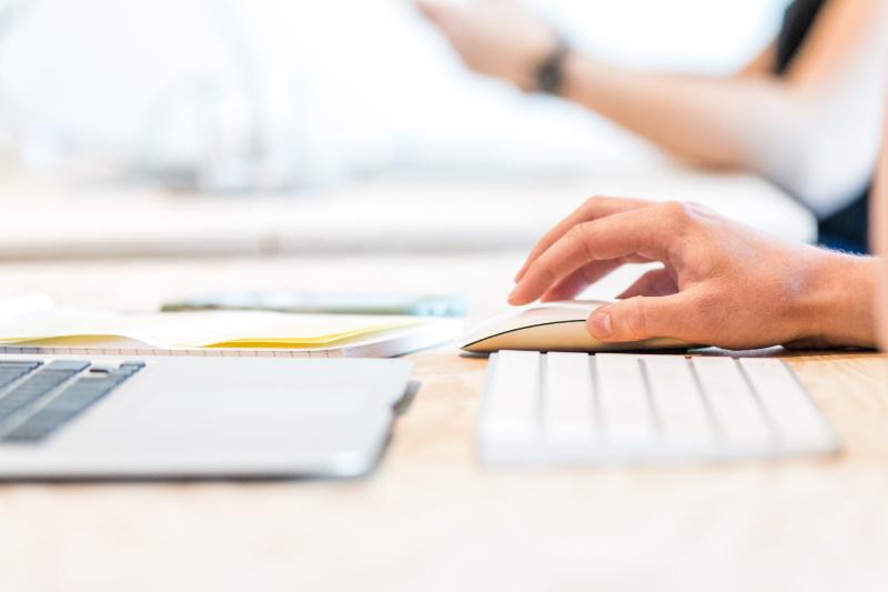 The hand of a person grasping a computer mouse.