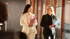 Two females in business attire walk through an office