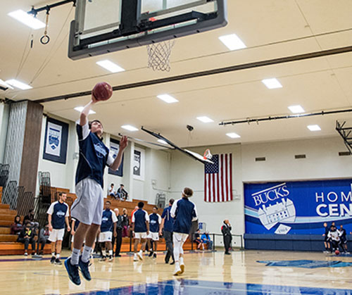A basketball player jumps in mid-air, holding a ball, ready to make a shot.