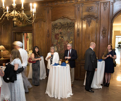 A group of people gathered around tables in a formal room, engaged in discussion.