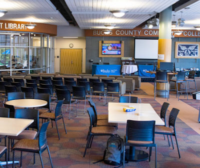 An expansive room with several tables and chairs, ready for a conference or social event.