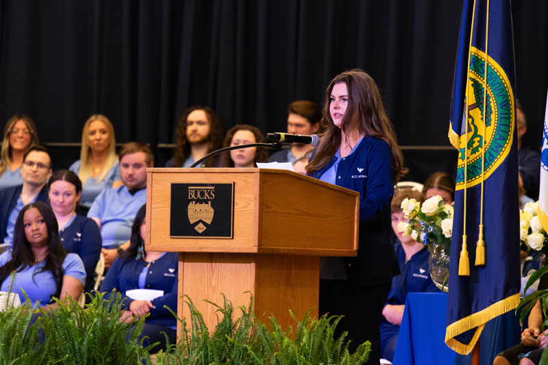 Sydney Doan speaks at a wooden podium labeled 