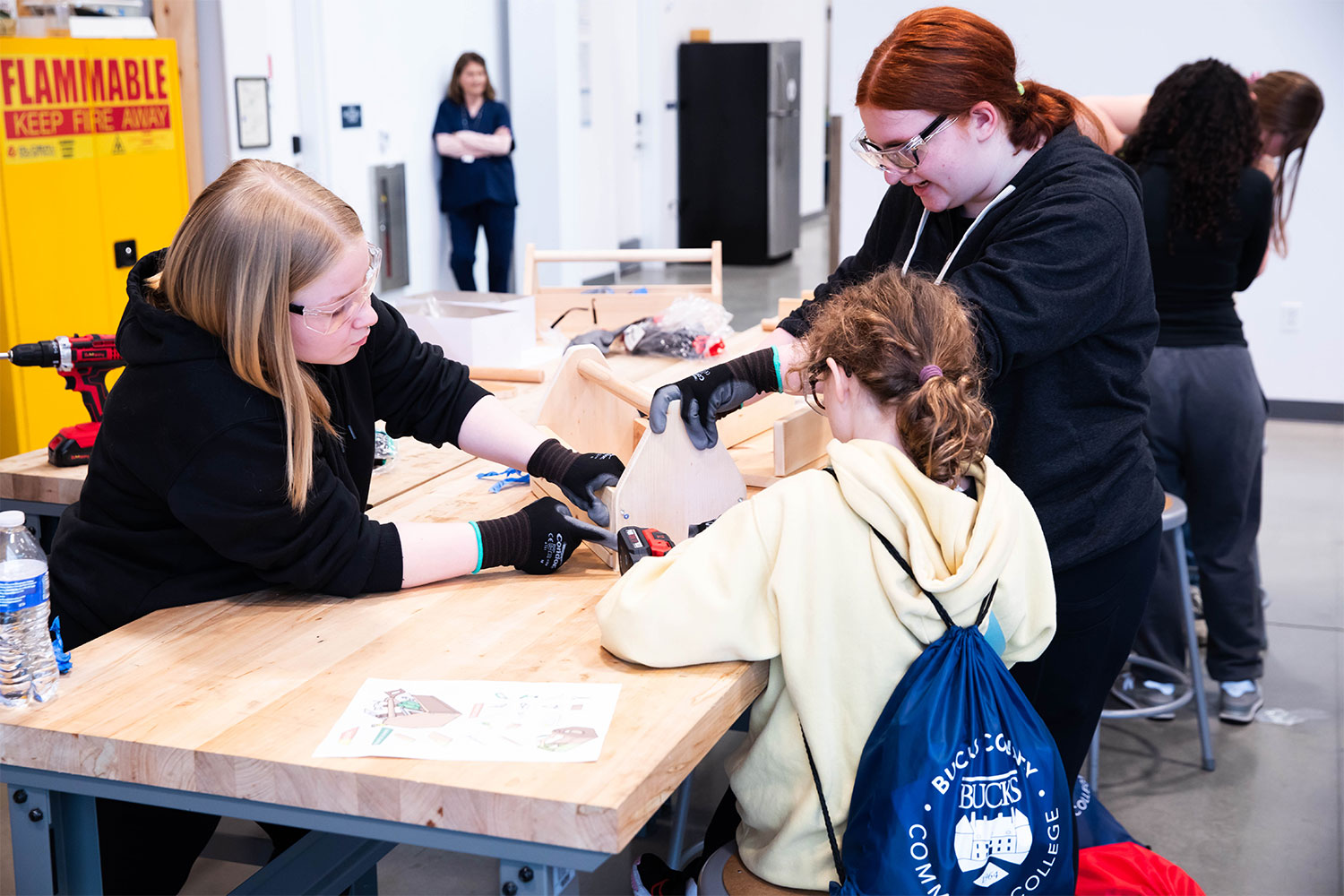 Young females at table trying woodworking tools