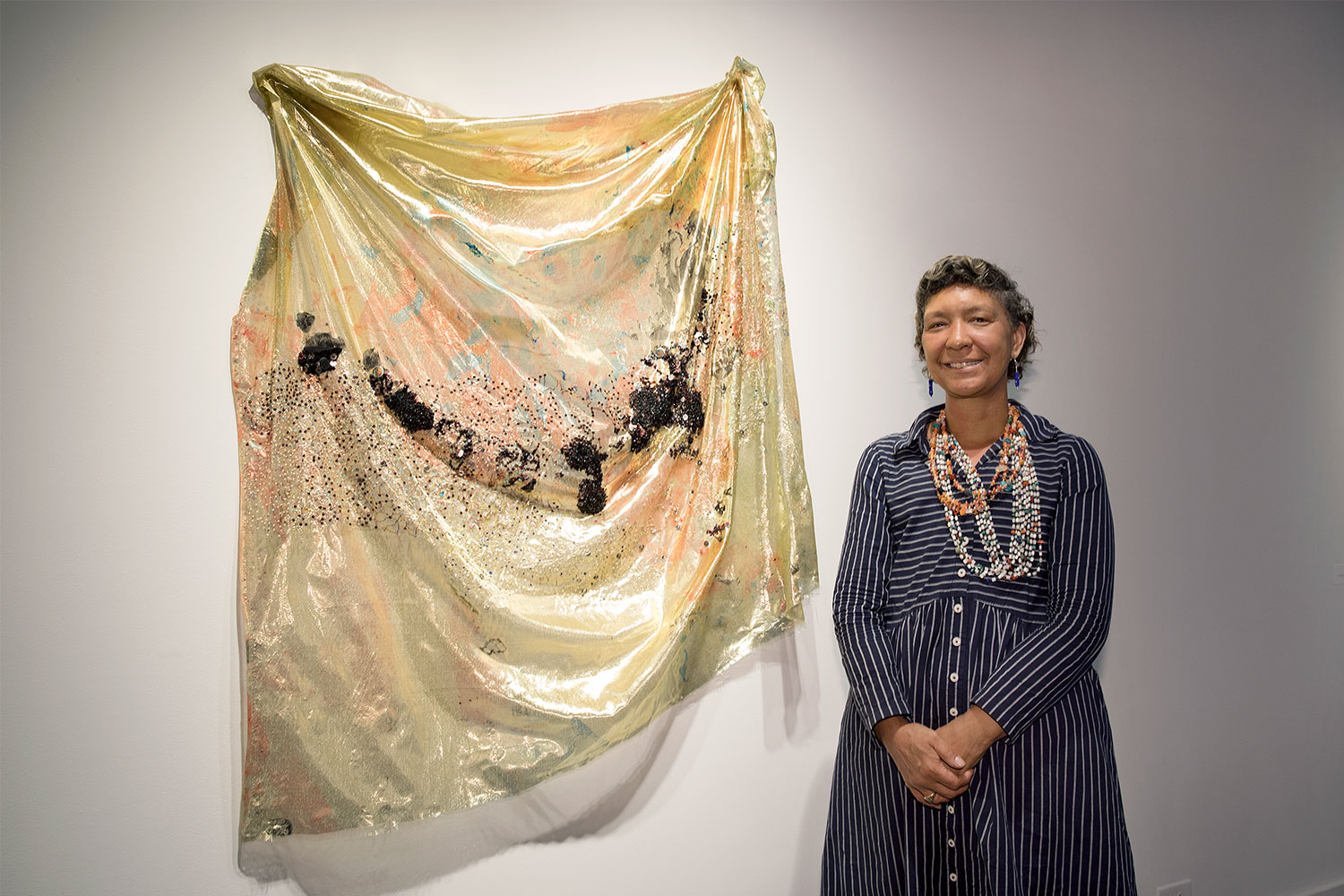 Artist Duwenavue Santé Johnson stands beside her textile work featured in “Visions of America” at Bucks County Community College's Hicks Art Center Gallery.