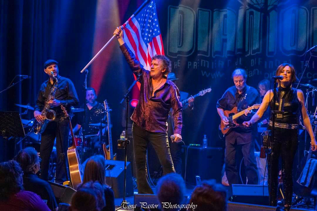vocalist on stage holding an american flag