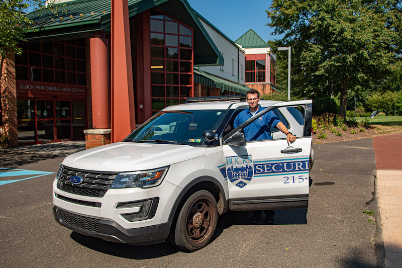 man standing outside of security suv
