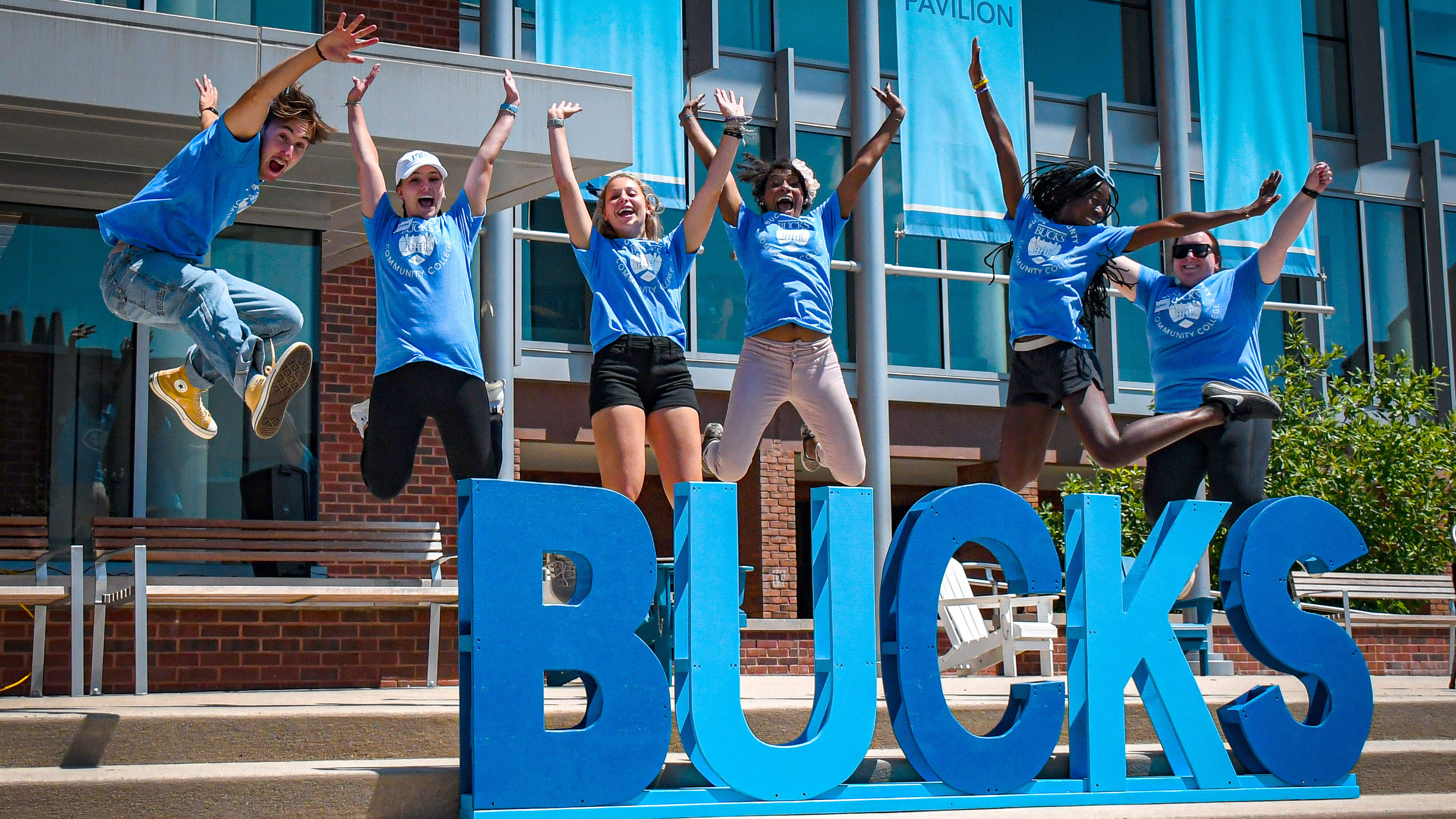 Excited group of students in blue Bucks t-shirts jumping in the air
