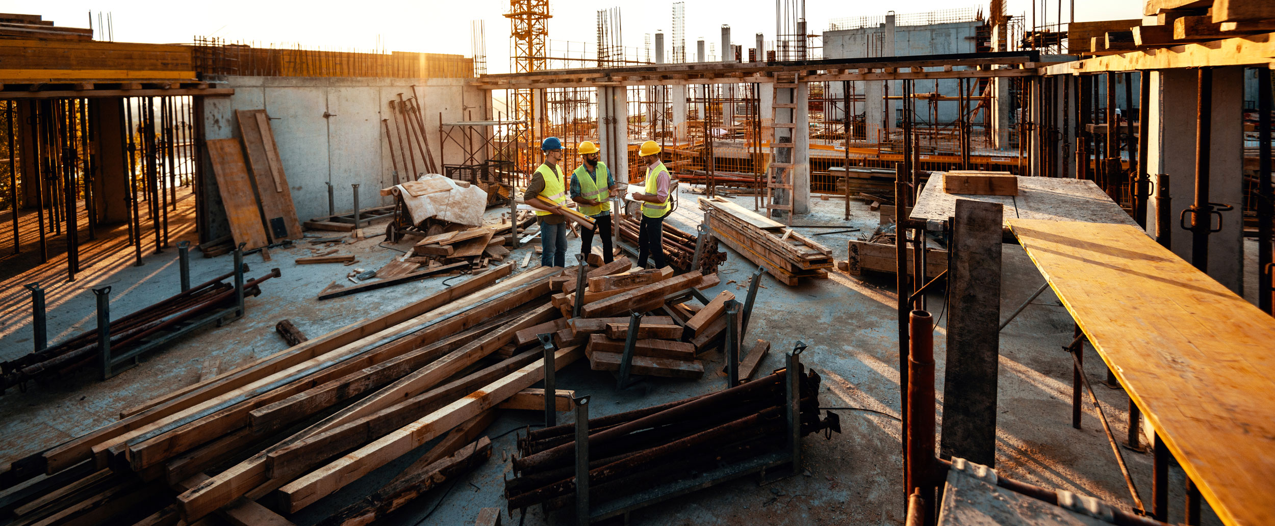 Three construction workers meeting in the middle of construction site