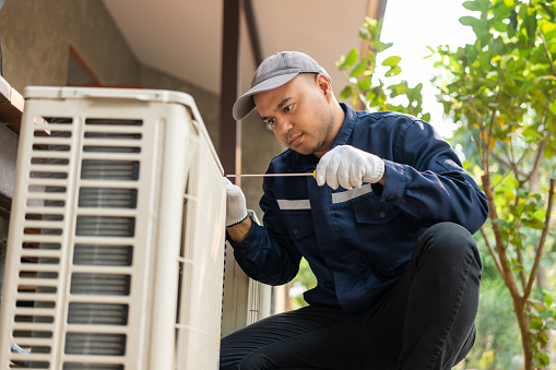 Male technician fixing outdoor air conditioning unit
