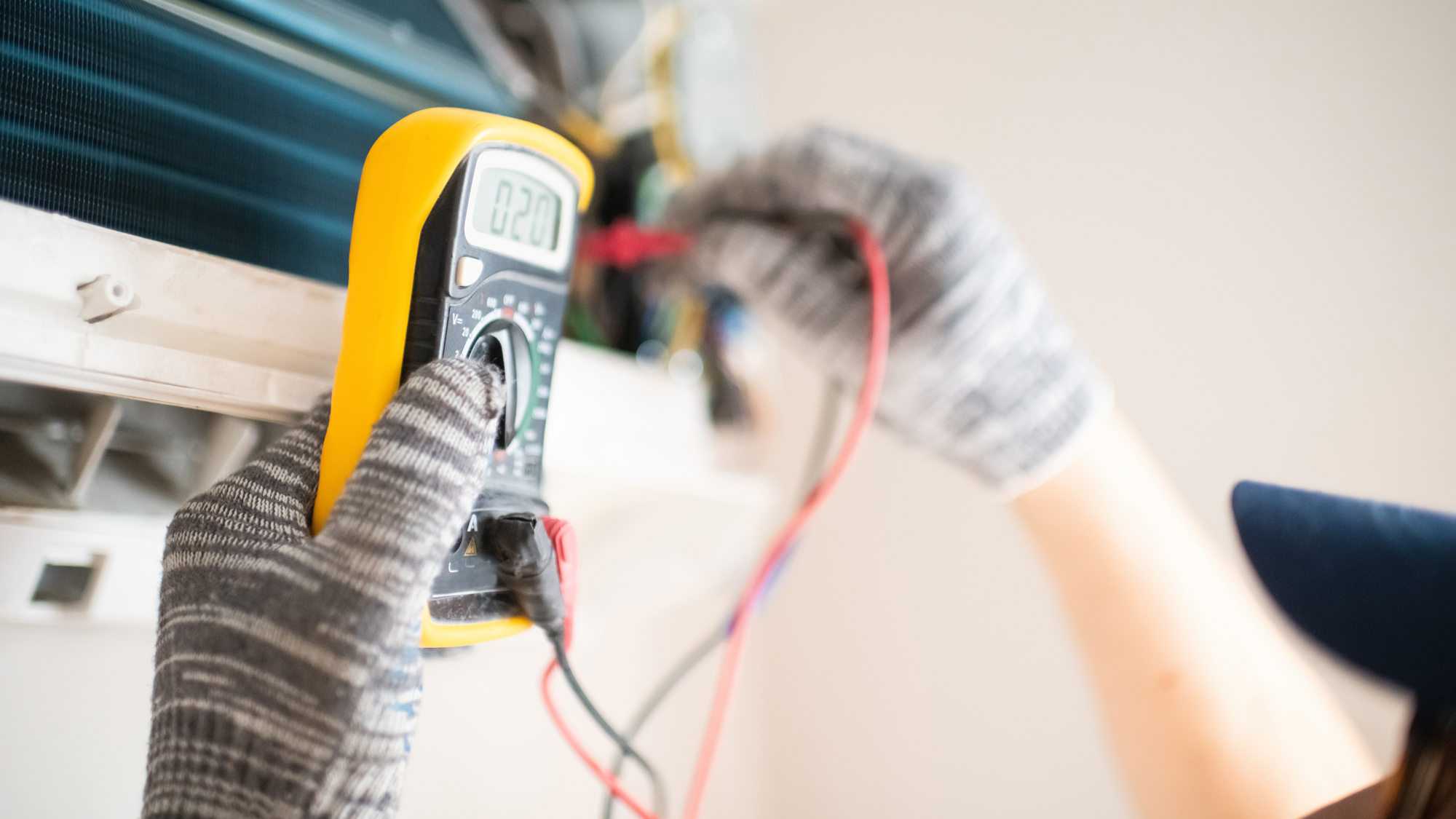 Technician with multimeter repairing air conditioner