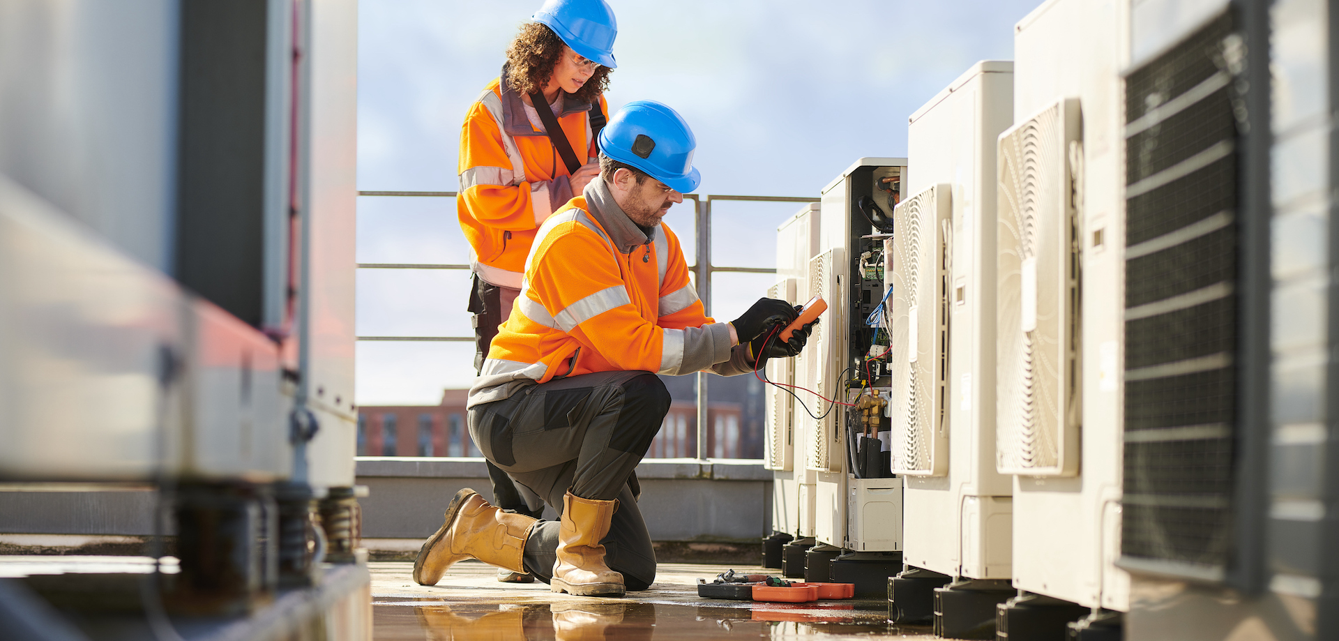 two people wearing safety gear working on industrial equipment